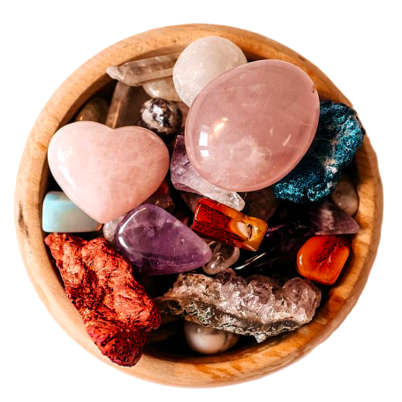 Small wooden bowl containing various coloured gems and crystals, seen from above. 