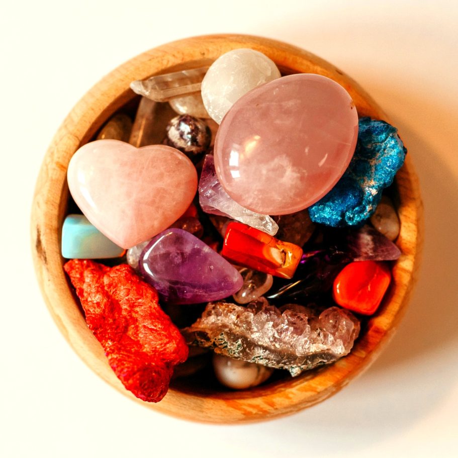 The Pebble Room logo with wooden bowl filled with colourful crystals viewed from above